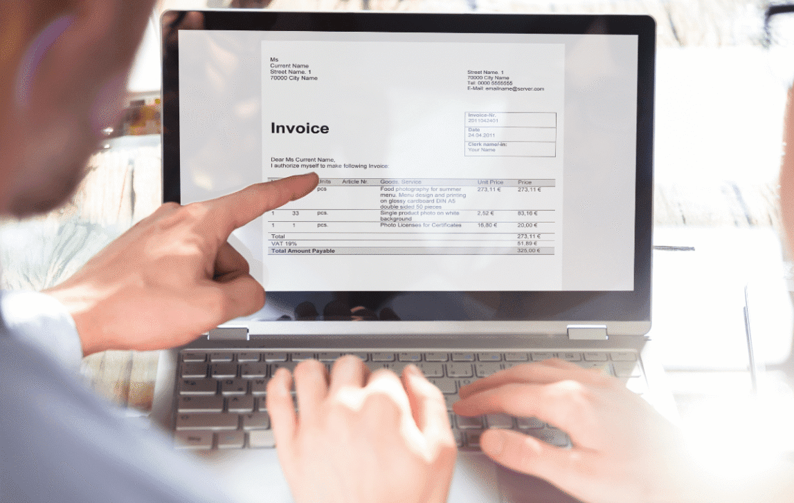 Person reviewing an invoice on a laptop, representing automated invoicing and financial workflows in NetSuite.