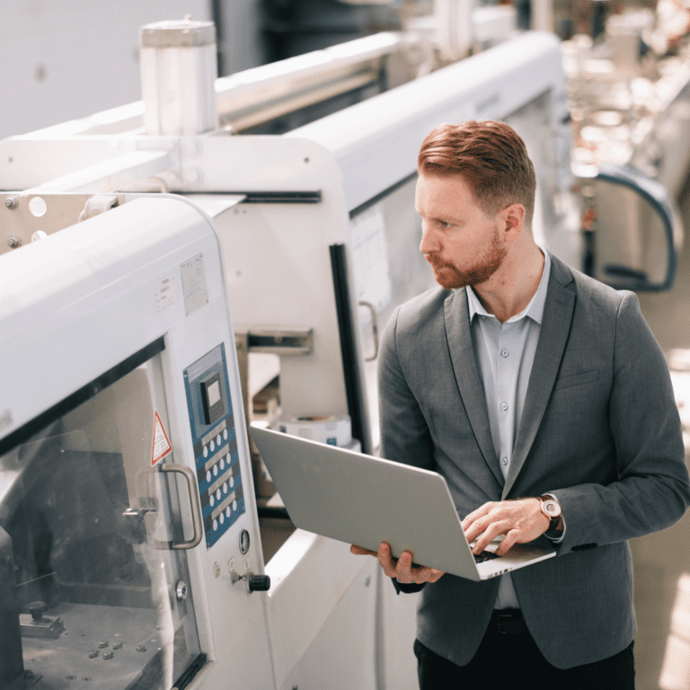 Man i kostym använder NetSuite ERP-system för att analysera produktion i tillverkande företag.