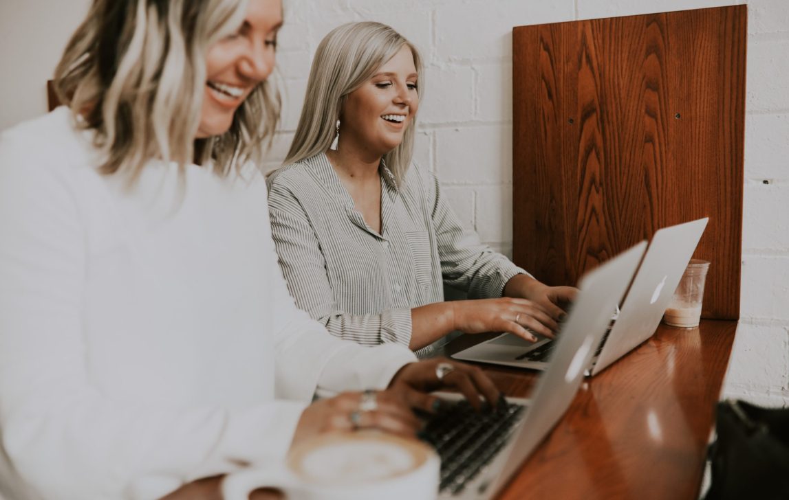 Two colleagues working on laptops together, representing streamlined collaboration and cloud ERP workflows in NetSuite.