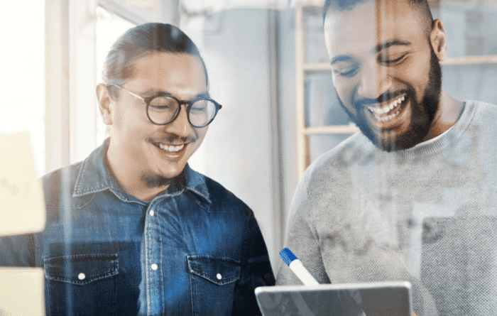 Två kollegor diskuterar en affärslösning i en modern kontorsmiljö, vilket illustrerar hur SuiteCloud gör NetSuite tryggt att anpassa för specialiserade företag.