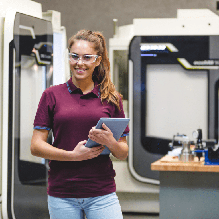 Kvinna i produktion som använder affärssystem på surfplatta i en tillverkande verksamhet.