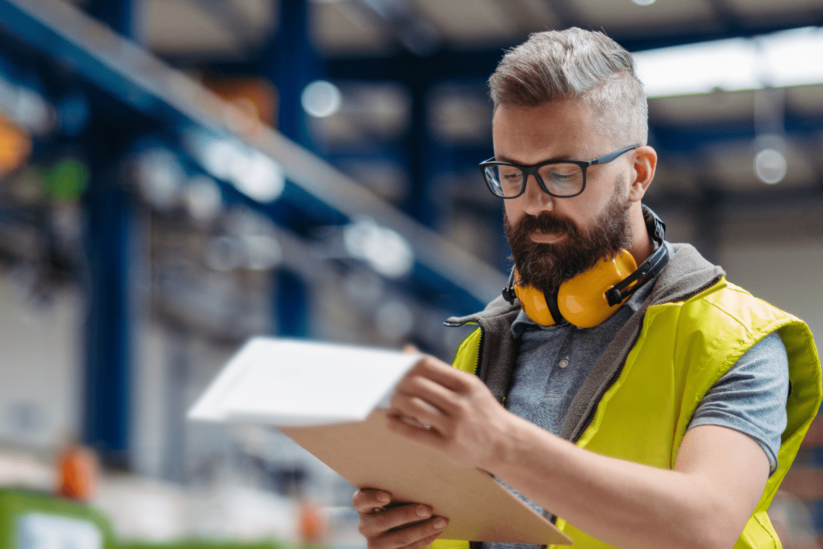 Produktionsmedarbetare i fabrik granskar dokument som del av uppföljning av KPI:er för tillverkning och lagerstyrning.