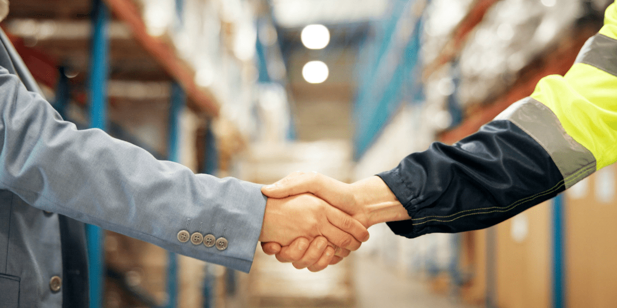 Affärsmöte mellan två representanter i ett tillverkande företag som skakar hand efter B2B-förhandling om samarbete och lönsam tillväxt.