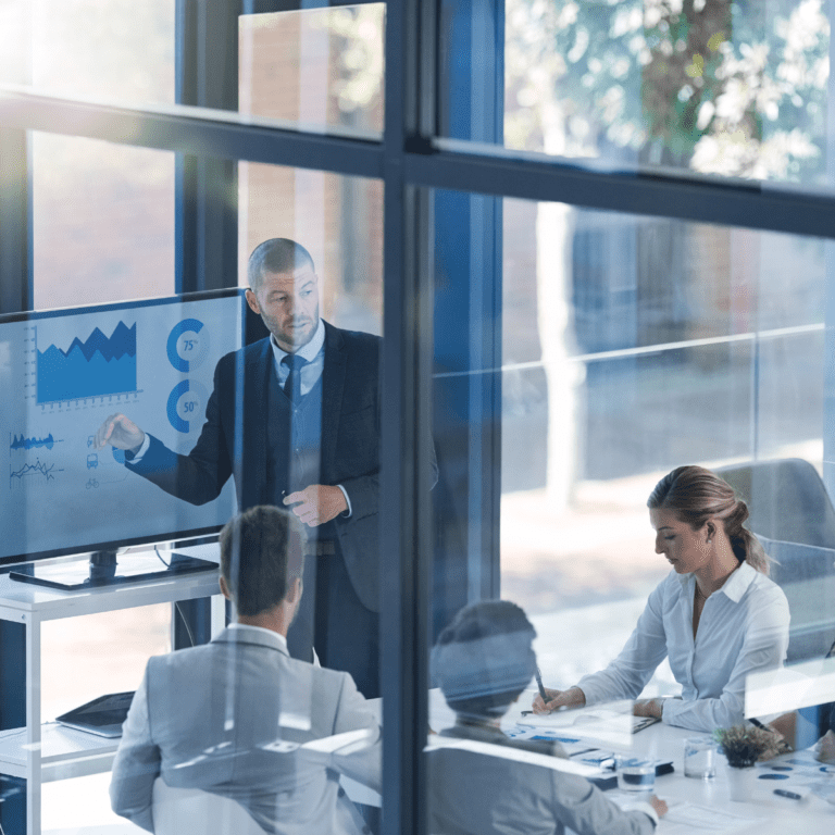 Ledningsgrupp i tillverkande företag analyserar lönsamhet och nyckeltal på skärm under strategimöte om effektivitet och vinsttillväxt.