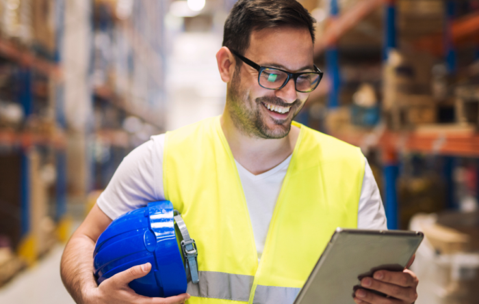 Lagerchef använder en surfplatta i ett modernt lager med höga pallställ för att hantera lager och logistik i NetSuite affärssystem för grossister och distributörer.